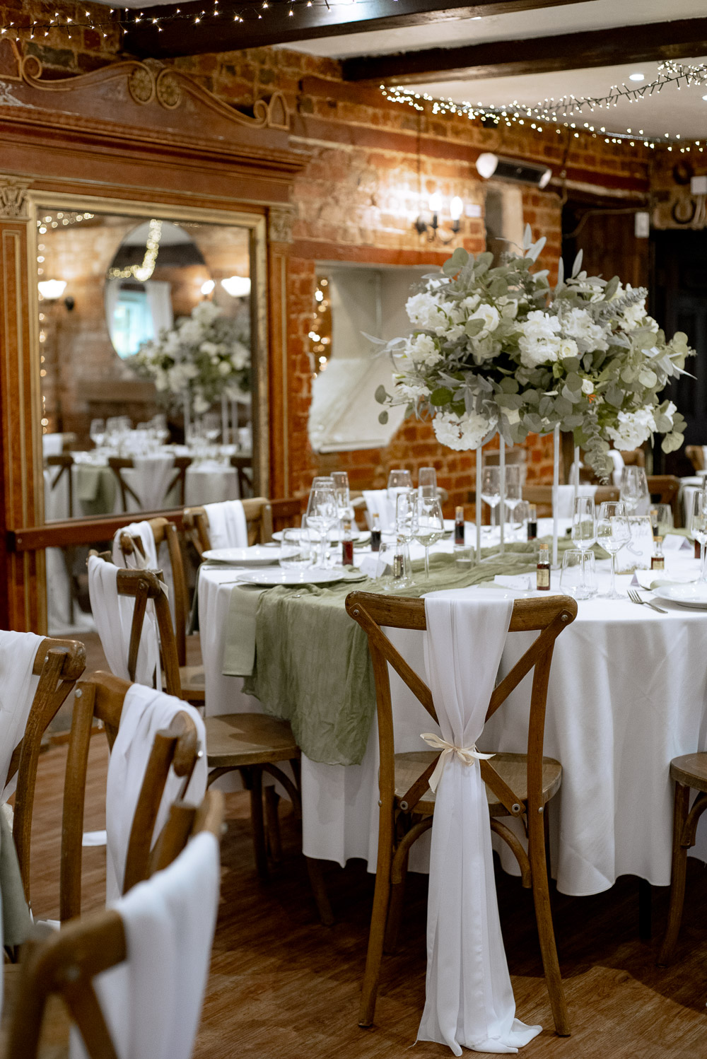 The Old Mill Aldermaston Wedding Nicola Belson Photography Fabric Chair Backs Green Linen White Roses Greenery Decor Tall Centrepiece